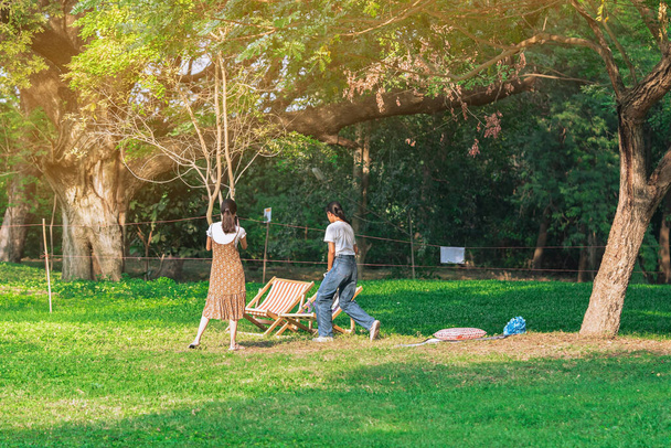 Takaisin näkymä Aasian nainen ystävien kävely yhdessä nurmikolla läpi vihreä puutarha.Nainen rentouttava puistossa. Onnellisuus ystävät viettävät aikaa yhdessä ulkona vihreässä luonnossa. Luonnosta nauttiminen ulkona. - Valokuva, kuva