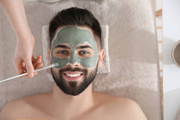 Cosmetologist applying mask on man's face in spa salon, top view - Fotoğraf, Görsel