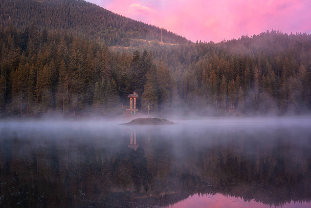 Fiery sunrise at alpine lake Synevyr, Carpathian mountains, amazing nature landscape with morning mist, forest, colored sky and reflection in the water, outdoor travel background, Zakarpattia, Ukraine - Photo, Image