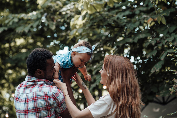 Família feliz brincando com a menina bonito no parque de verão durante o dia - Foto, Imagem