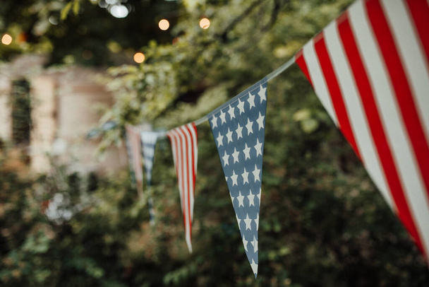 Színes zászlók amerikai stílusban lógott kötélen, elmosódott park háttér  - Fotó, kép