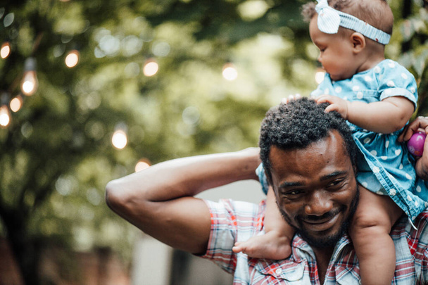 Счастливый отец держит милую дочь в летнем парке. Концепция счастливого родительства  - Фото, изображение