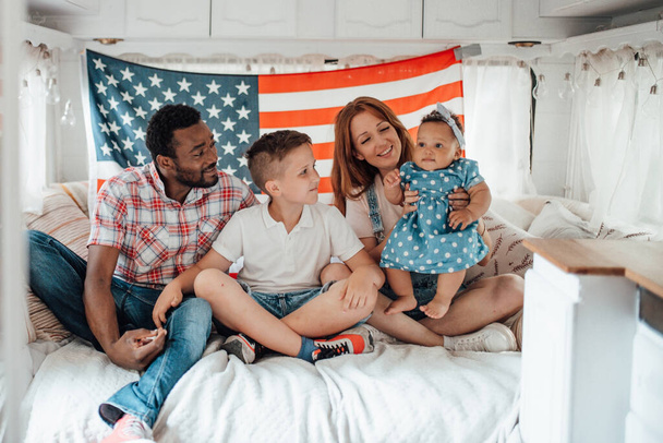 Happy rodina sedí na pohovce v přívěsu interiéru s americkou vlajkou na pozadí - Fotografie, Obrázek