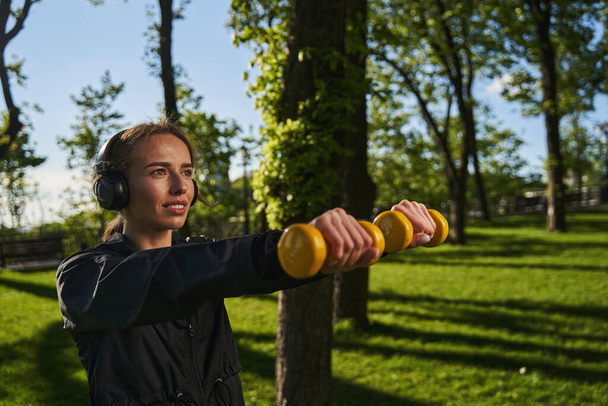 Vidám női testmozgás súlyzókkal a napos parkban - Fotó, kép