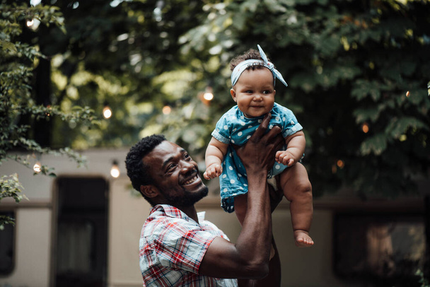 Ευτυχισμένος πατέρας που κρατάει την χαριτωμένη κόρη του στο πάρκο. Χαρούμενη έννοια της πατρότητας  - Φωτογραφία, εικόνα