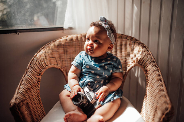 Retrato de menina bonito em roupas azuis sentado em poltrona com câmera nas mãos  - Foto, Imagem