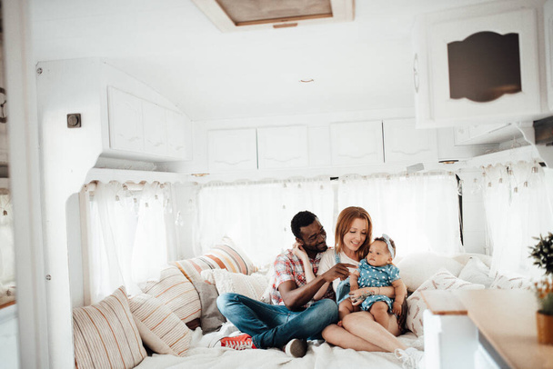 Loving family with little daughter sitting on sofa in trailer interior  - Foto, afbeelding