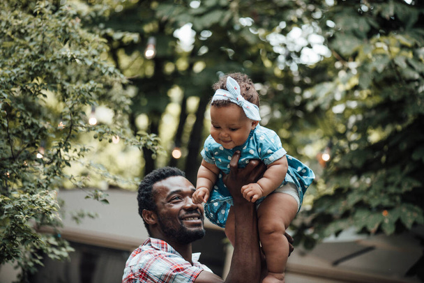 Szczęśliwy ojciec trzyma uroczą córkę w letnim parku. Koncepcja szczęśliwego rodzicielstwa  - Zdjęcie, obraz