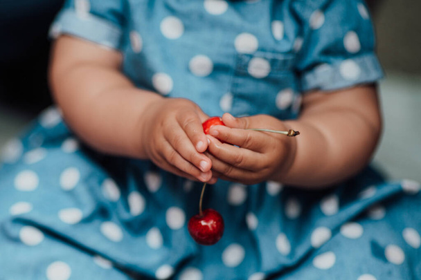 Sezione ritagliata di bambina con in mano ciliegie rosse  - Foto, immagini