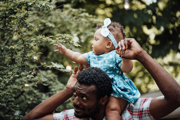 Happy father holding cute daughter in summer park. Happy parenthood concept  - Фото, изображение