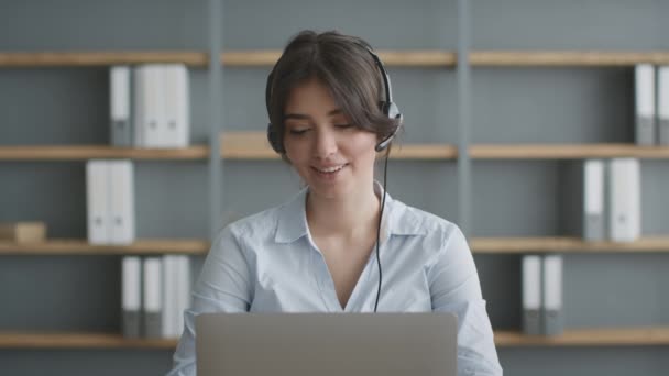 Telewerk concept. Jonge hotline operator draagt headset consulting client op afstand, praten en werken aan laptopmotion - Video
