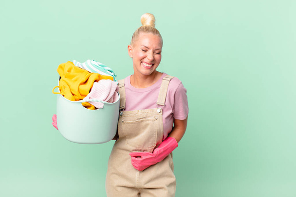 pretty blond woman laughing out loud at some hilarious joke washing clothes concept - Fotó, kép