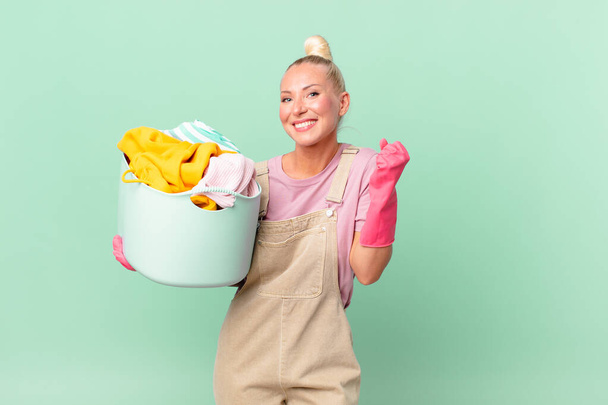 pretty blond woman feeling shocked,laughing and celebrating success washing clothes concept - Foto, Imagem