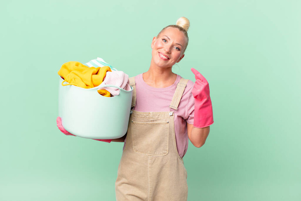 pretty blond woman smiling confidently pointing to own broad smile washing clothes concept - Foto, Imagen