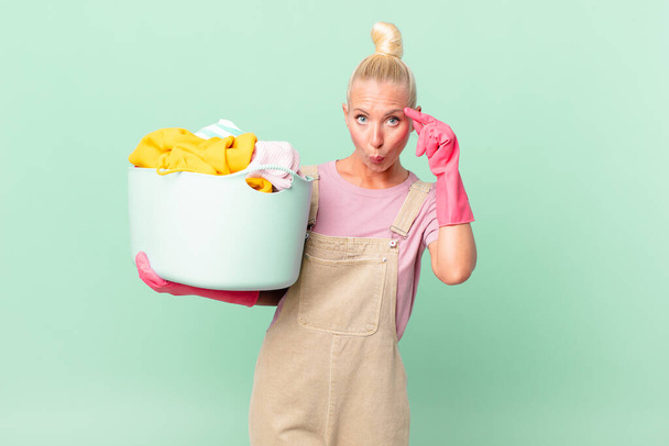 pretty blond woman looking surprised, realizing a new thought, idea or concept washing clothes concept - Photo, Image