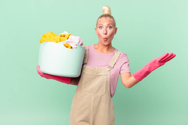 pretty blond woman amazed, shocked and astonished with an unbelievable surprise washing clothes concept - Photo, Image