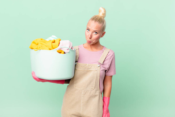 pretty blond woman feeling sad and whiney with an unhappy look and crying washing clothes concept - Фото, изображение