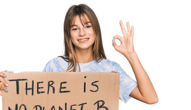 Teenager caucasico ragazza in possesso non c'è pianeta b banner facendo ok segno con le dita, sorridente amichevole gesticolando eccellente simbolo  - Foto, immagini
