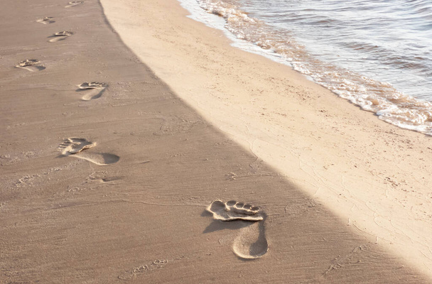 Следы на песке на берегу моря, оставленные уходящим человеком, горизонтальный выстрел - Фото, изображение