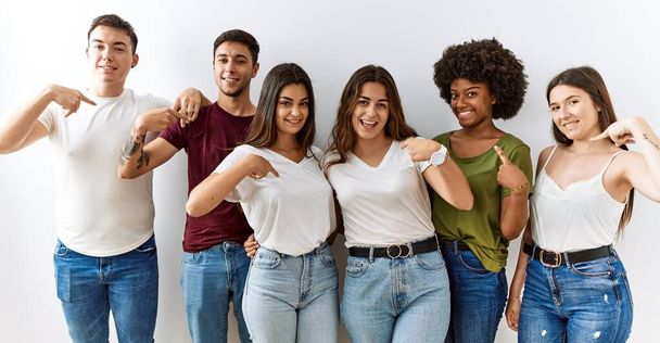 Group of young friends standing together over isolated background looking confident with smile on face, pointing oneself with fingers proud and happy.  - Photo, image