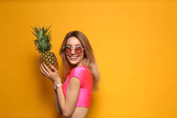 Young woman with fresh pineapple on yellow background, space for text. Exotic fruit - Valokuva, kuva