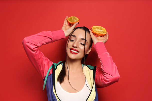 Young woman with fresh kiwano on red background. Exotic fruit - Φωτογραφία, εικόνα