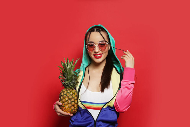 Молодая женщина со свежим ананасом на красном фоне. Экзотические фрукты - Фото, изображение