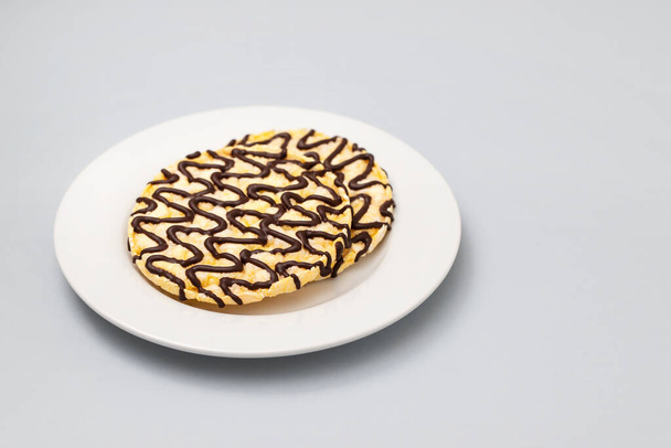 corn crackers with lines of chocolate on white plate on ceramic background - Photo, Image