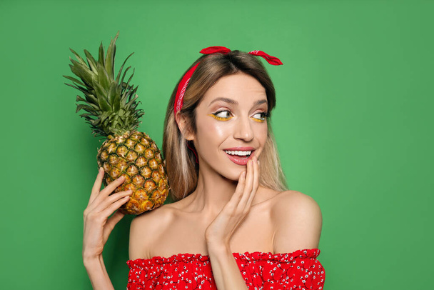 Young woman with fresh pineapple on green background. Exotic fruit - Foto, Imagen
