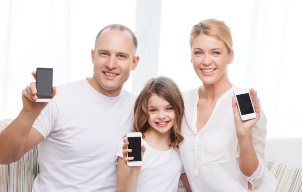 parents and little girl with smartphones at home - Foto, afbeelding
