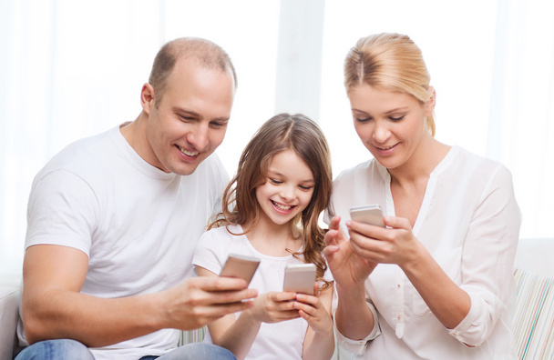Родители и маленькая девочка со смартфонами дома
 - Фото, изображение