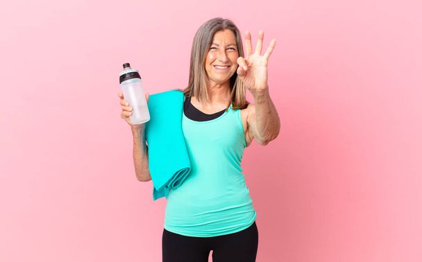 pretty middle age woman smiling and looking friendly, showing number three. fitness concept - Fotoğraf, Görsel