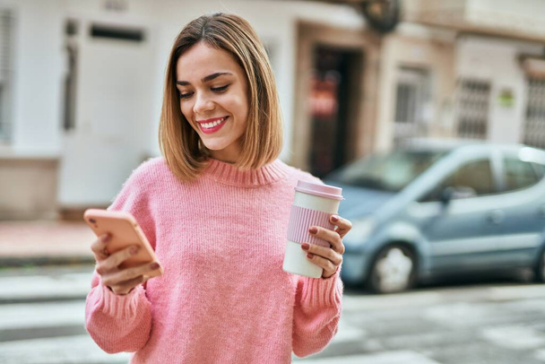 Giovane ragazza caucasica utilizzando smartphone e bere caffè in città. - Foto, immagini