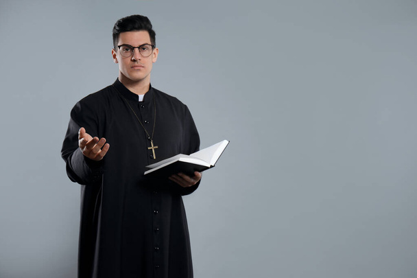 Priest with Bible on grey background. Space for text - Fotoğraf, Görsel
