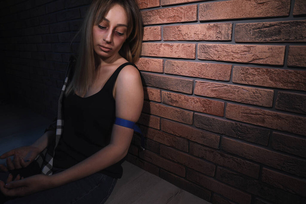 Donna drogata in overdose vicino al muro di mattoni. Spazio per testo - Foto, immagini