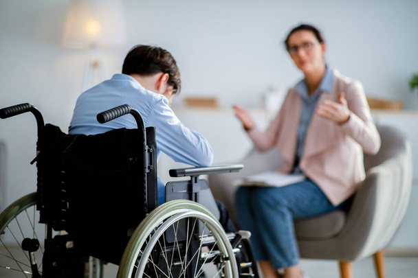 Psychologische hulp voor gehandicapten. Gehandicapte adolescent huilend tijdens overleg met psychotherapeut op kantoor - Foto, afbeelding