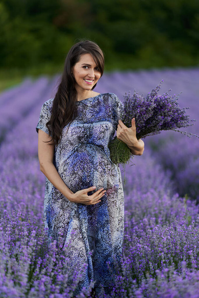 Beautiful young pregnant woman in a lavender field in full bloom - Фото, зображення