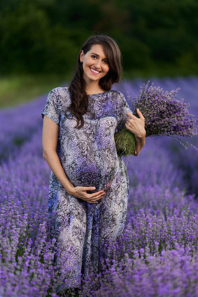Beautiful young pregnant woman in a lavender field in full bloom - Фото, зображення