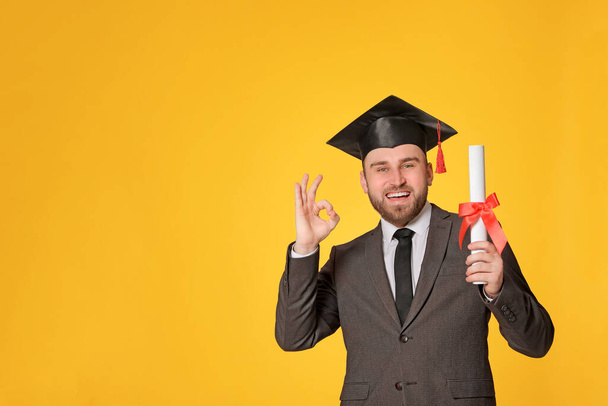 Happy student with graduation hat and diploma on yellow background. Space for text - Фото, изображение