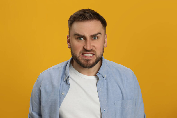 Angry young man on yellow background. Hate concept - Фото, зображення