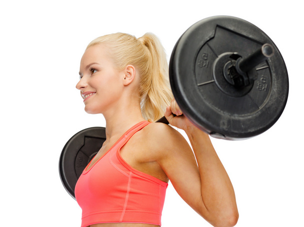 smiling sporty woman exercising with barbell - Фото, зображення