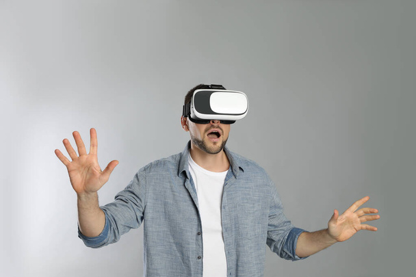 Man using virtual reality headset on grey background - Photo, image