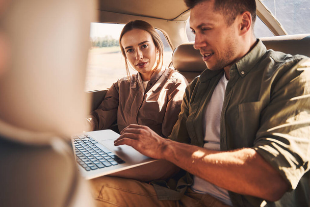 Beautiful young couple using laptop in car - Φωτογραφία, εικόνα