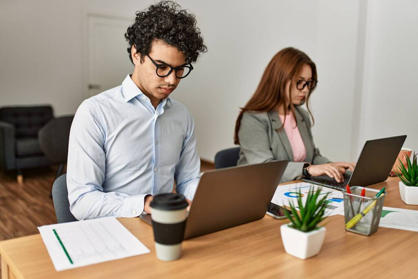 Deux travailleurs d'affaires avec une expression sérieuse travaillant à l'aide d'un ordinateur portable au bureau. - Photo, image