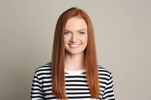 Candid portrait of happy young woman with charming smile and gorgeous red hair on beige background - Foto, Imagem