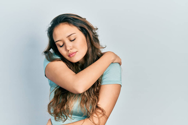 Jeune fille hispanique portant chemise décontractée s'embrassant heureux et positif, souriant confiant. amour de soi et soins de soi  - Photo, image