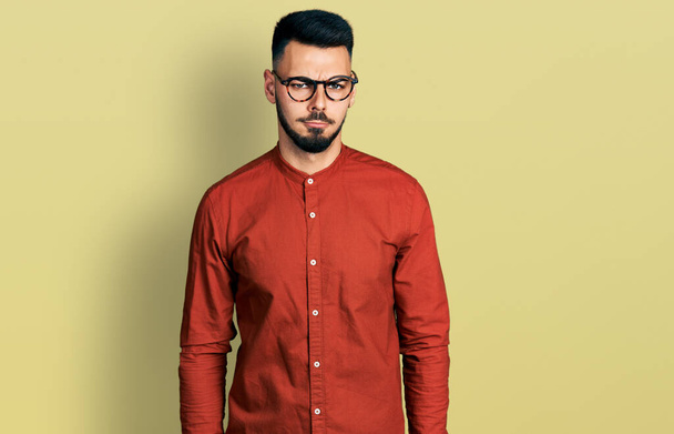 Junger hispanischer Mann mit Bart, Businesshemd und Brille, skeptisch und nervös, die Stirn runzelnd wegen des Problems. negative person.  - Foto, Bild