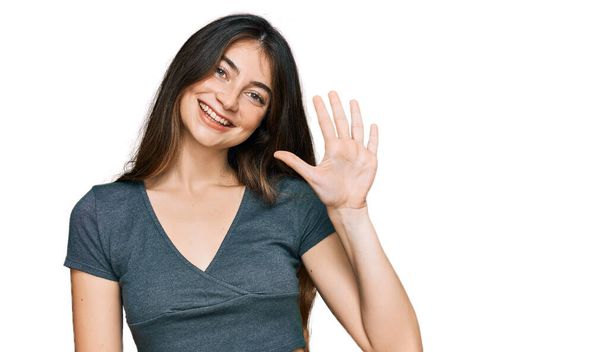 Jovem bela menina adolescente vestindo casual top t shirt mostrando e apontando para cima com os dedos número cinco, sorrindo confiante e feliz.  - Foto, Imagem