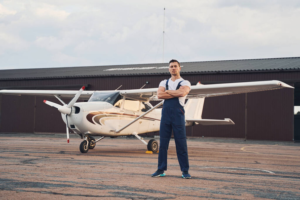 Athletic male worker standing near aircraft at airdrome - Photo, Image