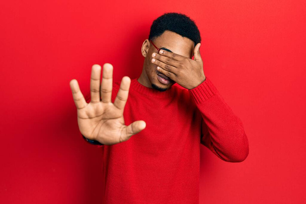 Young african american man wearing casual clothes and glasses covering eyes with hands and doing stop gesture with sad and fear expression. embarrassed and negative concept.  - Photo, Image